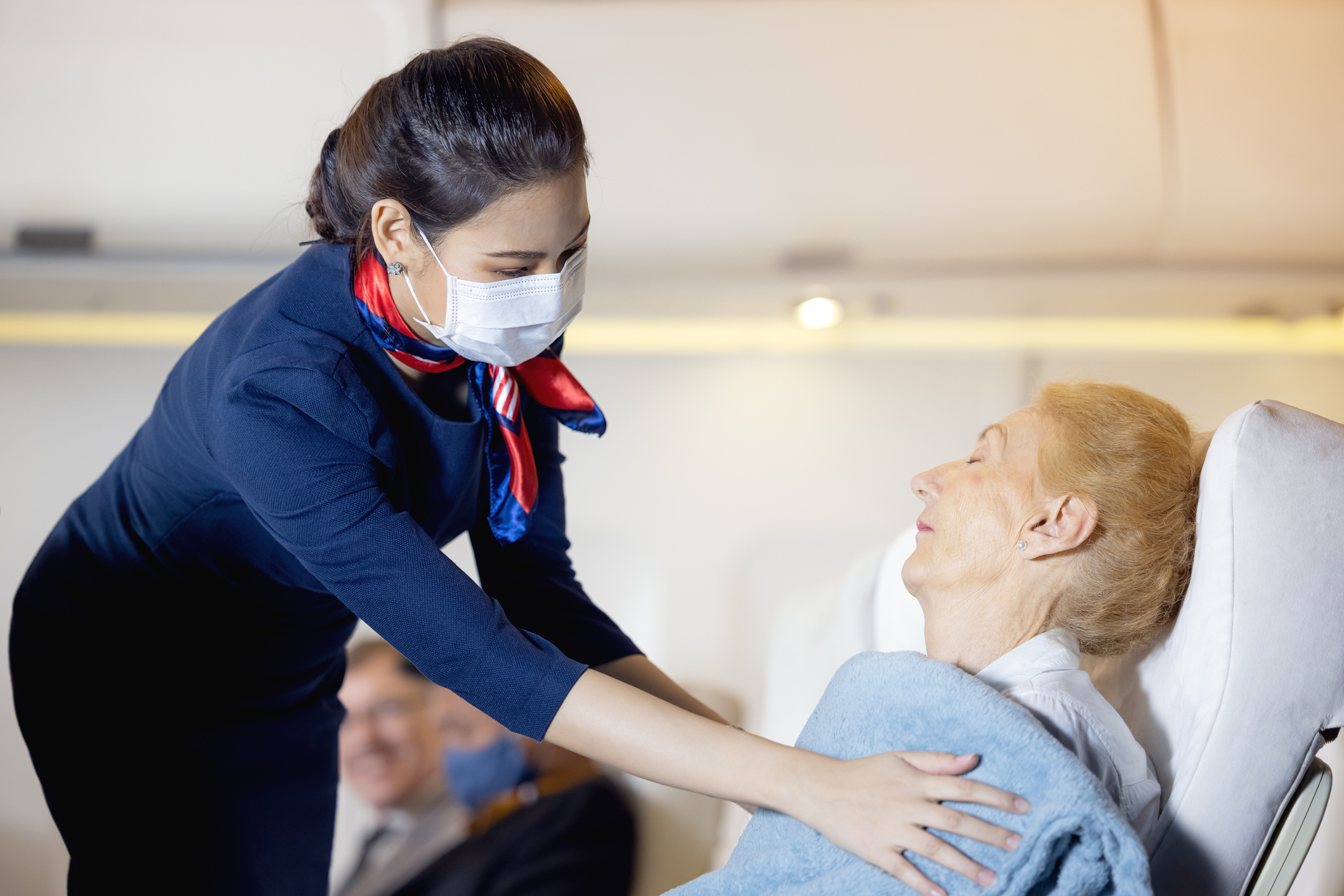 A female flight attendant clothed an elderly passenger