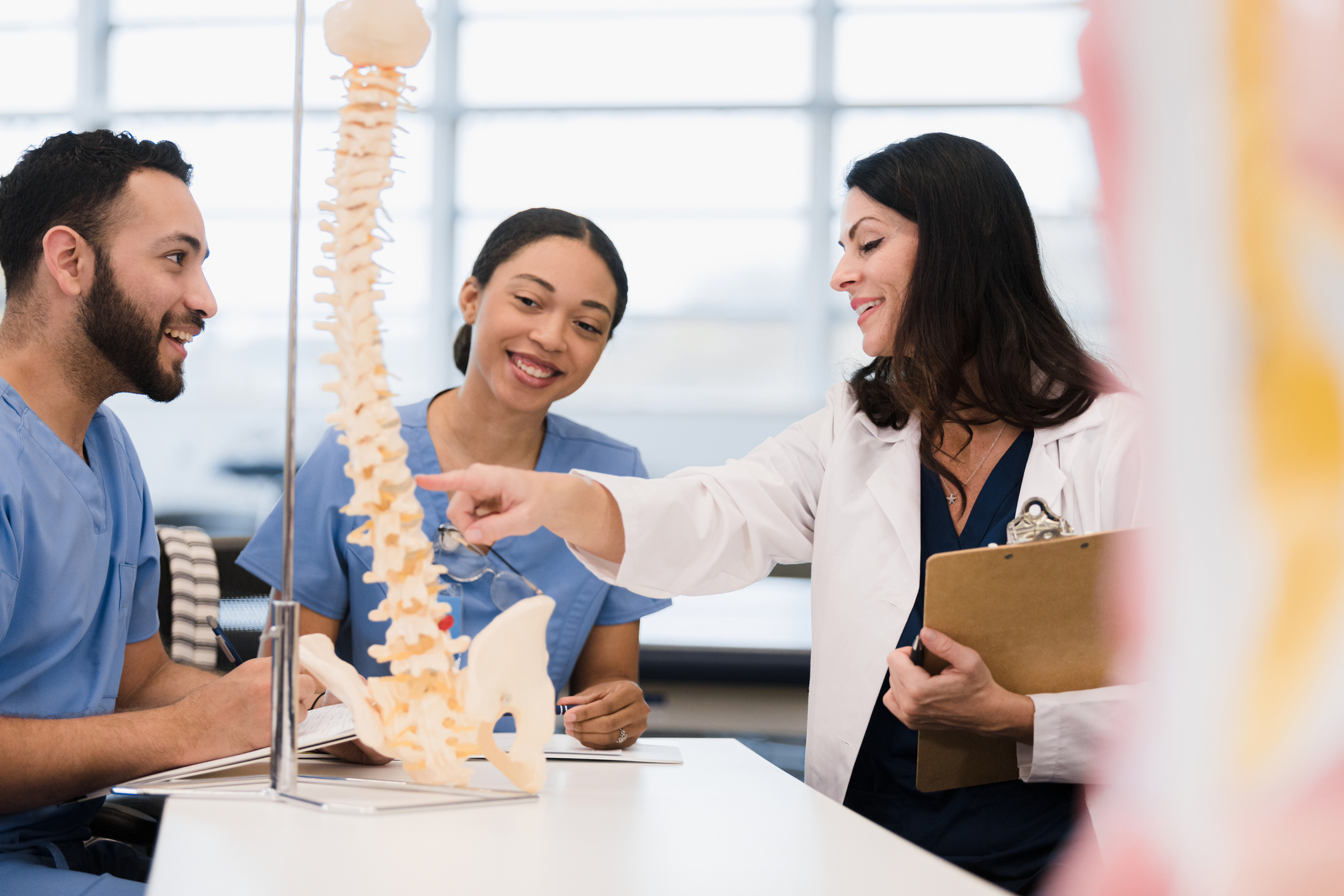 doctor and nurses looking at model of spine