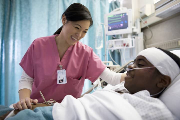 nurse speaking with a patient in hospital bed