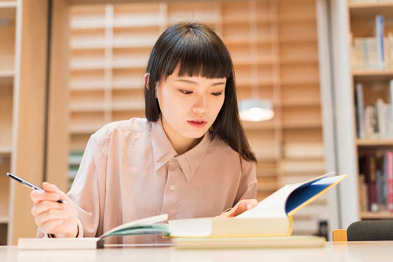 woman sitting at desk studying with books
